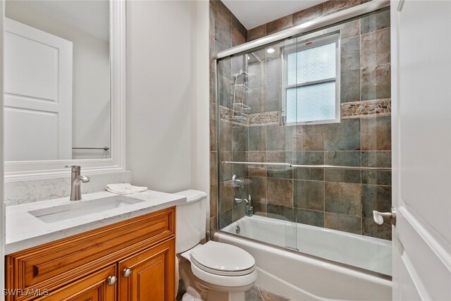 full bathroom featuring vanity, toilet, and bath / shower combo with glass door