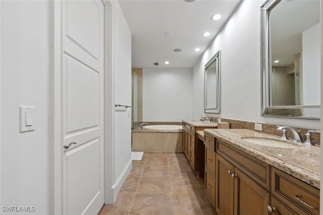 bathroom with tile patterned flooring, a relaxing tiled tub, and vanity