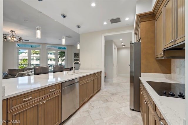 kitchen with french doors, sink, light stone countertops, appliances with stainless steel finishes, and decorative light fixtures