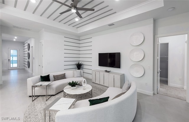 living room featuring light tile patterned floors, a tray ceiling, ceiling fan, and ornamental molding