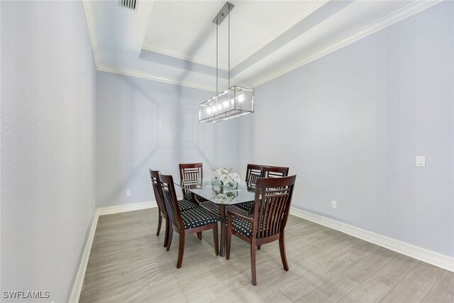 dining room with a chandelier, a tray ceiling, light hardwood / wood-style flooring, and crown molding