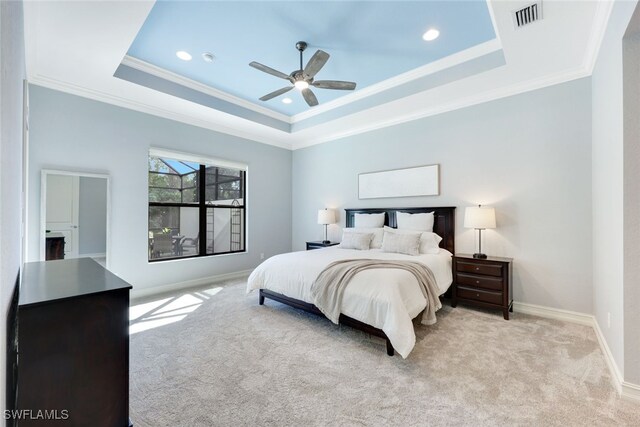 carpeted bedroom featuring a raised ceiling, ceiling fan, and ornamental molding