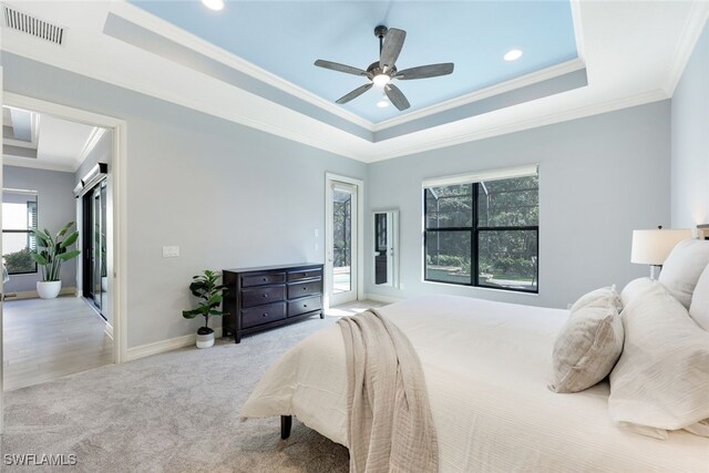 carpeted bedroom with a tray ceiling, access to exterior, ceiling fan, and ornamental molding