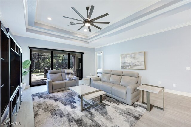 living room featuring light hardwood / wood-style flooring, a raised ceiling, ceiling fan, and crown molding