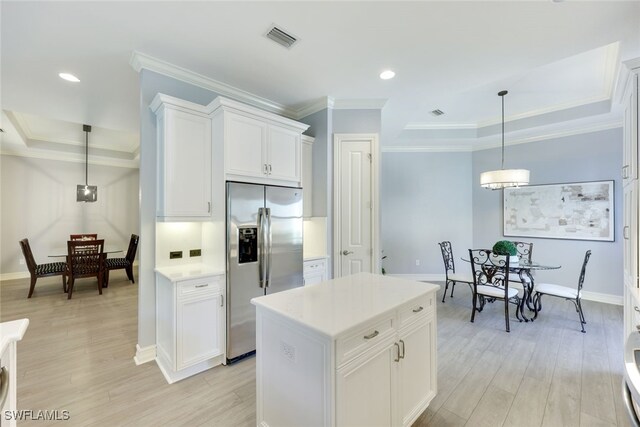 kitchen with stainless steel refrigerator with ice dispenser, a kitchen island, white cabinetry, and pendant lighting