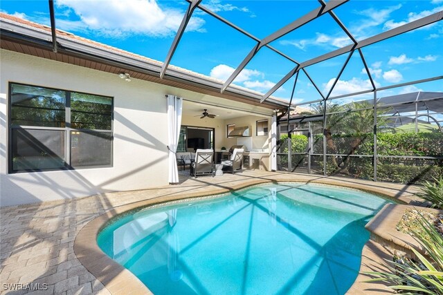 view of swimming pool with ceiling fan, a patio area, and glass enclosure