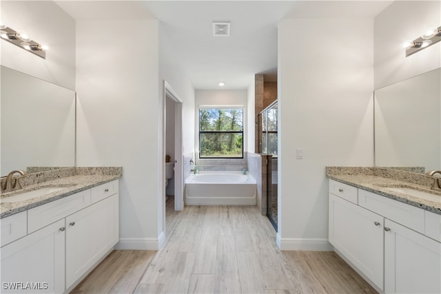 full bathroom featuring hardwood / wood-style floors, vanity, toilet, and independent shower and bath