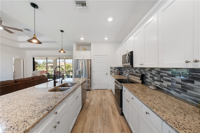 kitchen featuring white cabinetry, sink, tasteful backsplash, light hardwood / wood-style floors, and appliances with stainless steel finishes