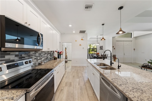 kitchen with sink, stainless steel appliances, light stone counters, light hardwood / wood-style floors, and white cabinets