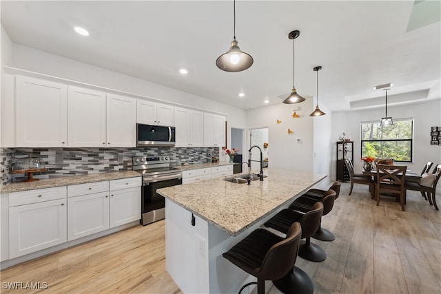 kitchen with white cabinets, stainless steel appliances, hanging light fixtures, and sink