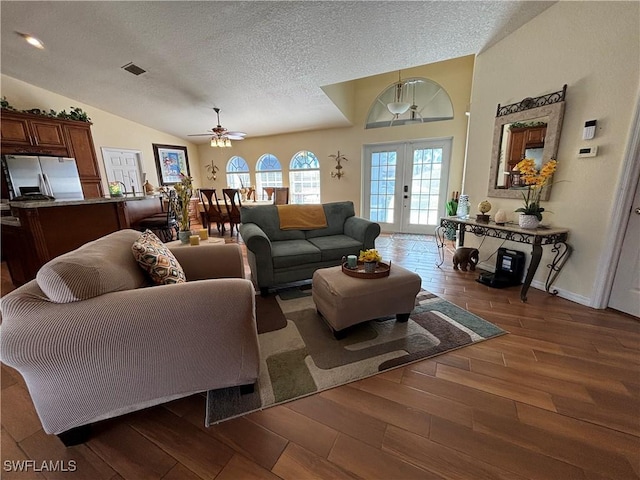 living room featuring french doors, vaulted ceiling, dark hardwood / wood-style floors, ceiling fan, and a textured ceiling