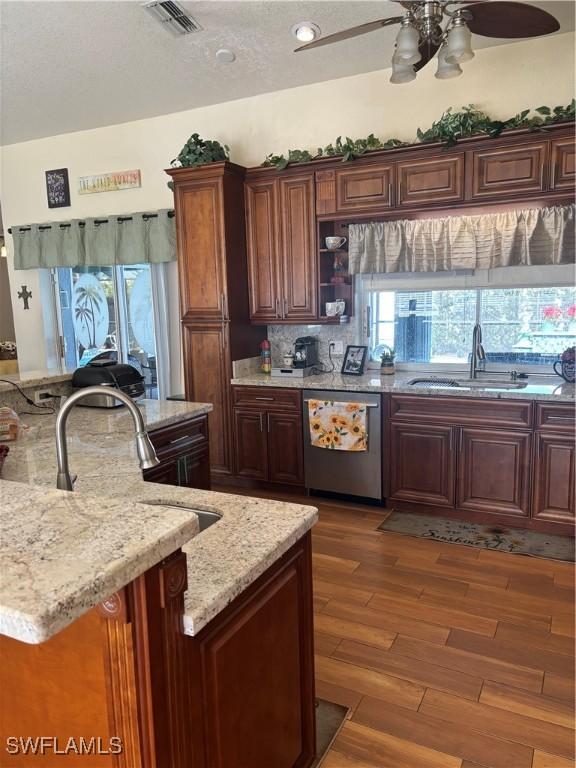 kitchen featuring dishwasher, sink, dark hardwood / wood-style floors, ceiling fan, and light stone countertops