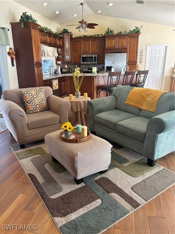 living room with ceiling fan, sink, dark wood-type flooring, and lofted ceiling