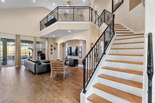 stairs with french doors, high vaulted ceiling, and hardwood / wood-style flooring