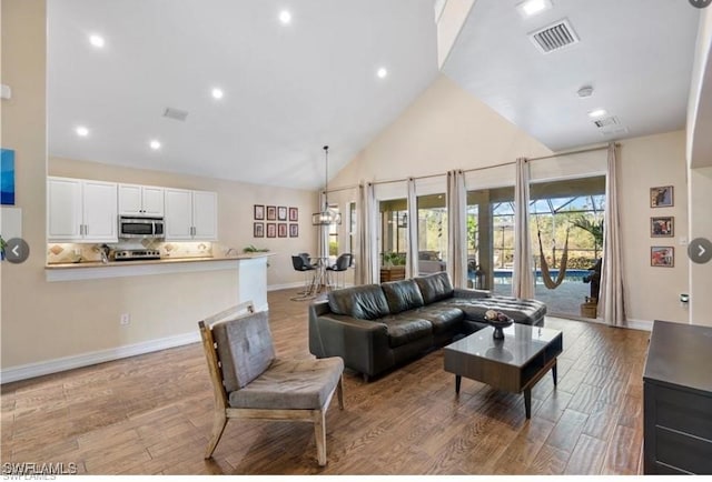 living room with light hardwood / wood-style floors and high vaulted ceiling