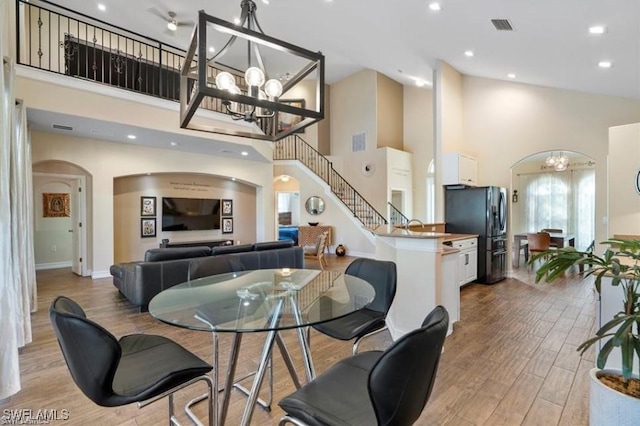 dining room with light hardwood / wood-style floors, high vaulted ceiling, and an inviting chandelier