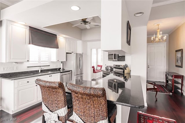 kitchen featuring white cabinetry, sink, kitchen peninsula, crown molding, and appliances with stainless steel finishes