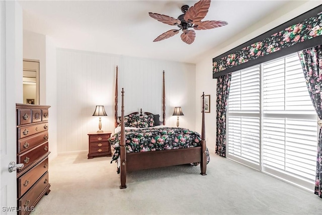 bedroom featuring light colored carpet, ceiling fan, and wood walls