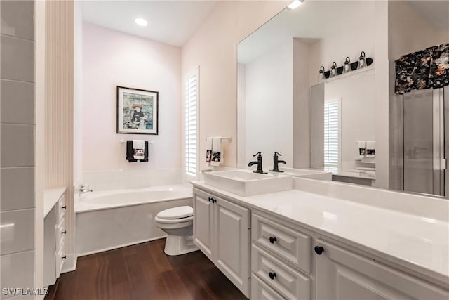 bathroom featuring a washtub, vanity, wood-type flooring, and toilet