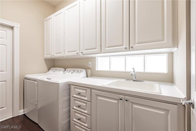 clothes washing area featuring cabinets, washing machine and dryer, dark hardwood / wood-style floors, and sink