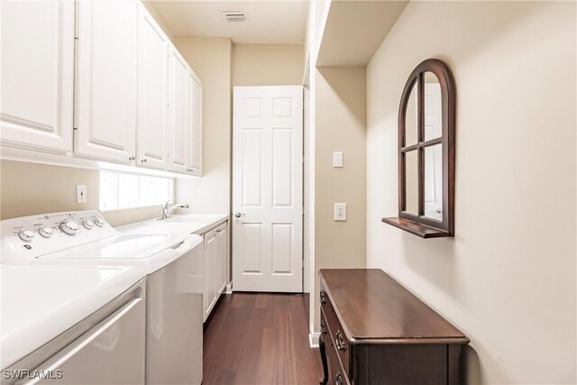 washroom with sink, cabinets, independent washer and dryer, and dark wood-type flooring