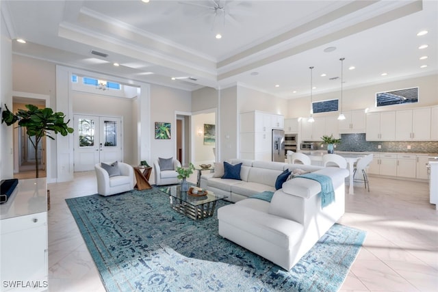 living room featuring ceiling fan, ornamental molding, a tray ceiling, and french doors