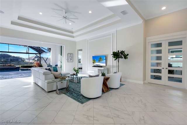 living room with french doors, a tray ceiling, ceiling fan, and ornamental molding