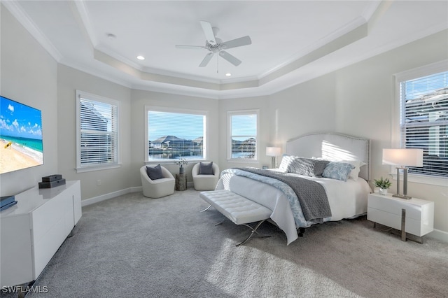 bedroom with ceiling fan, light colored carpet, a tray ceiling, and multiple windows