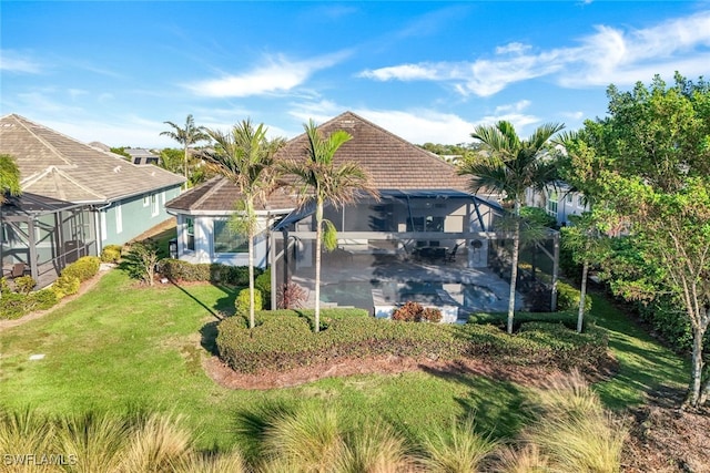 rear view of house featuring a patio, a yard, glass enclosure, and a swimming pool