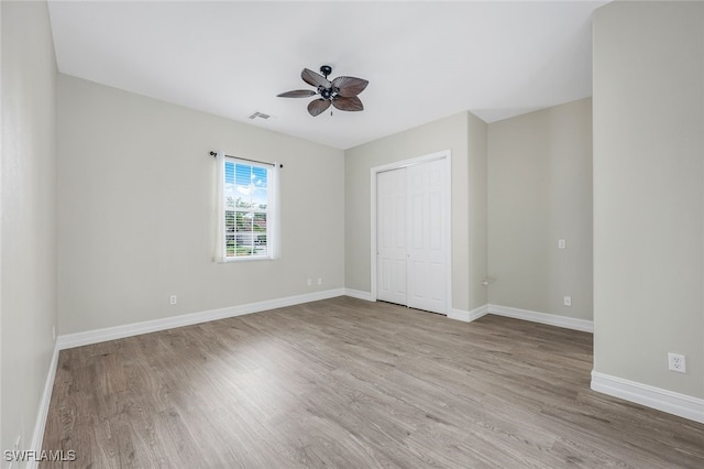 unfurnished bedroom with ceiling fan, a closet, and light wood-type flooring