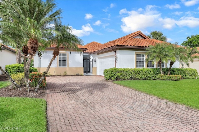 mediterranean / spanish home featuring a front lawn and a garage