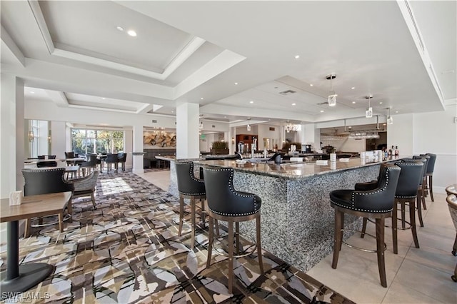 bar with decorative light fixtures, stone countertops, and a tray ceiling