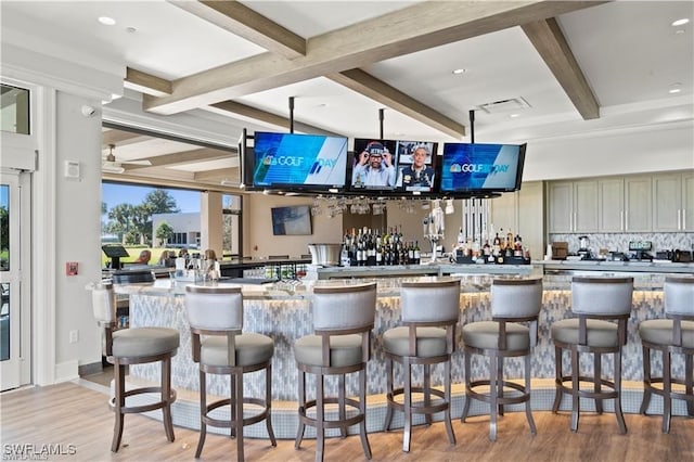 bar with light stone countertops, beam ceiling, light hardwood / wood-style floors, and ceiling fan