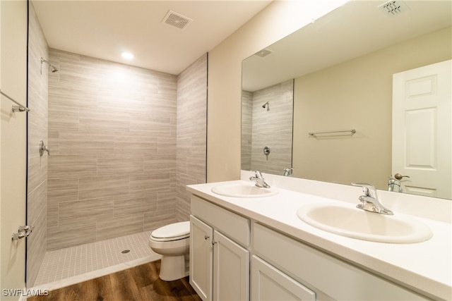 bathroom featuring tiled shower, vanity, hardwood / wood-style flooring, and toilet