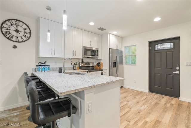 kitchen featuring white cabinets, sink, hanging light fixtures, kitchen peninsula, and stainless steel appliances