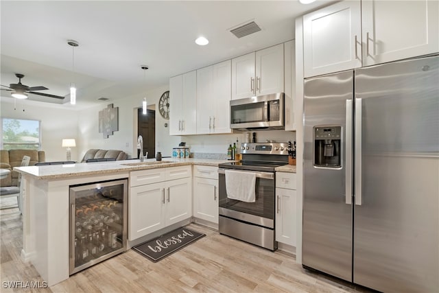 kitchen with stainless steel appliances, white cabinetry, beverage cooler, and sink