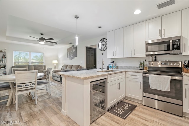 kitchen featuring white cabinetry, sink, beverage cooler, stainless steel appliances, and light wood-type flooring