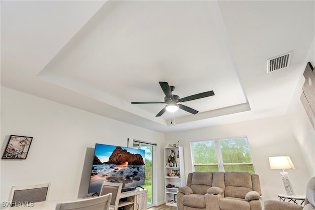 living room featuring a tray ceiling and ceiling fan