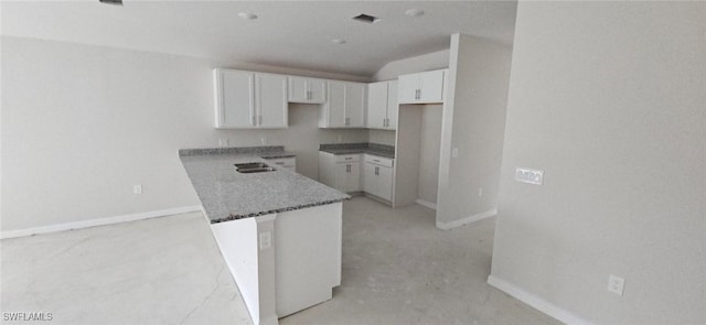 kitchen featuring stone counters, baseboards, and white cabinetry