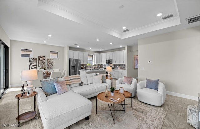 living room featuring a raised ceiling and crown molding