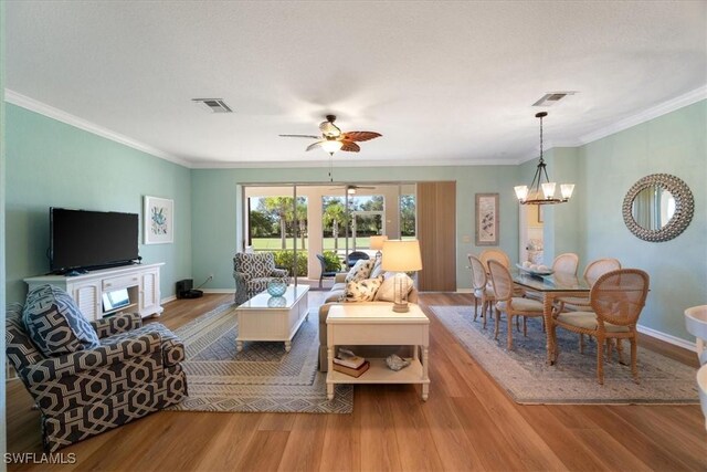 living room with a textured ceiling, ceiling fan with notable chandelier, light hardwood / wood-style floors, and crown molding