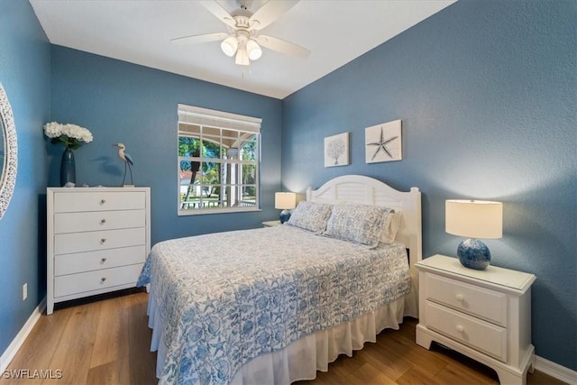 bedroom with a ceiling fan, baseboards, and wood finished floors