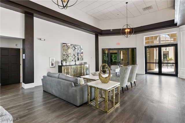 living room with french doors, a towering ceiling, a chandelier, and dark hardwood / wood-style floors