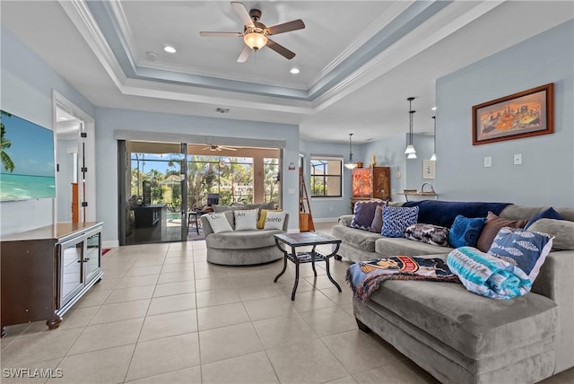 tiled living room with a raised ceiling, ceiling fan, and crown molding