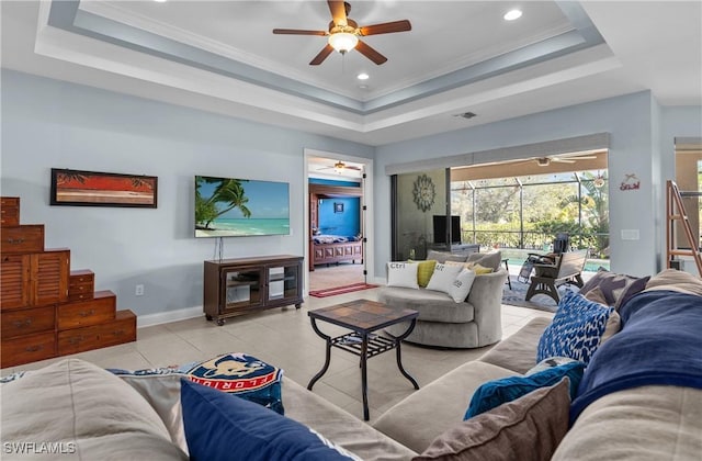 tiled living room with a raised ceiling, ceiling fan, and ornamental molding