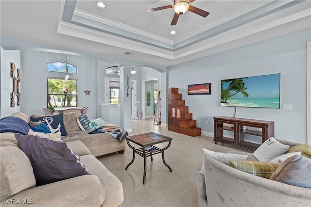 living room with a tray ceiling, ceiling fan, and ornamental molding