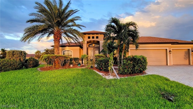 mediterranean / spanish home featuring a yard and a garage