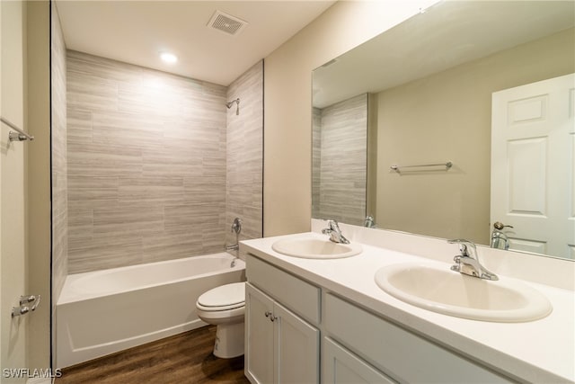 full bathroom featuring hardwood / wood-style flooring, vanity, tiled shower / bath combo, and toilet