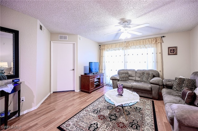 living room featuring ceiling fan, light hardwood / wood-style floors, and a textured ceiling