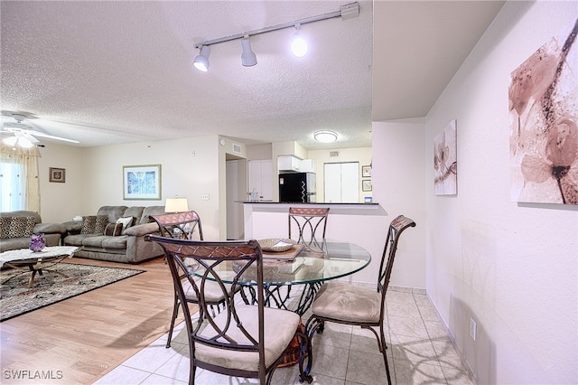 dining space with a textured ceiling, light hardwood / wood-style floors, ceiling fan, and rail lighting